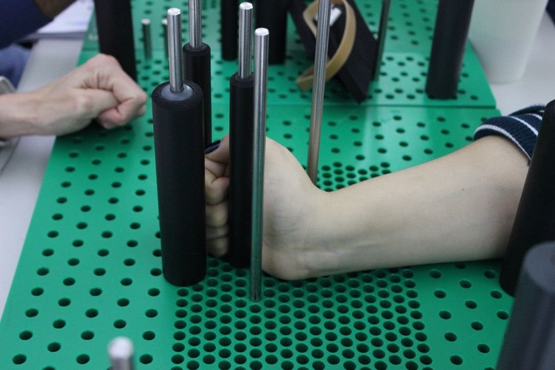 Paciente haciendo un ejercicio de agarre con cilindros en la tabla canadiense durante su rehabilitación de mano en RehabiliTO