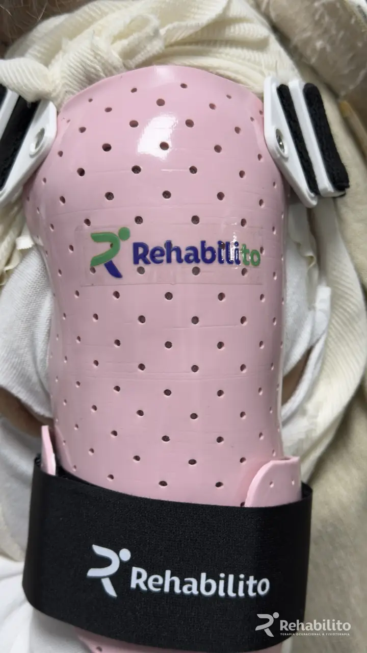 Detalle de una férula personalizada de hombro y brazo en termoplástico rosa perforado con el logo de RehabiliTO